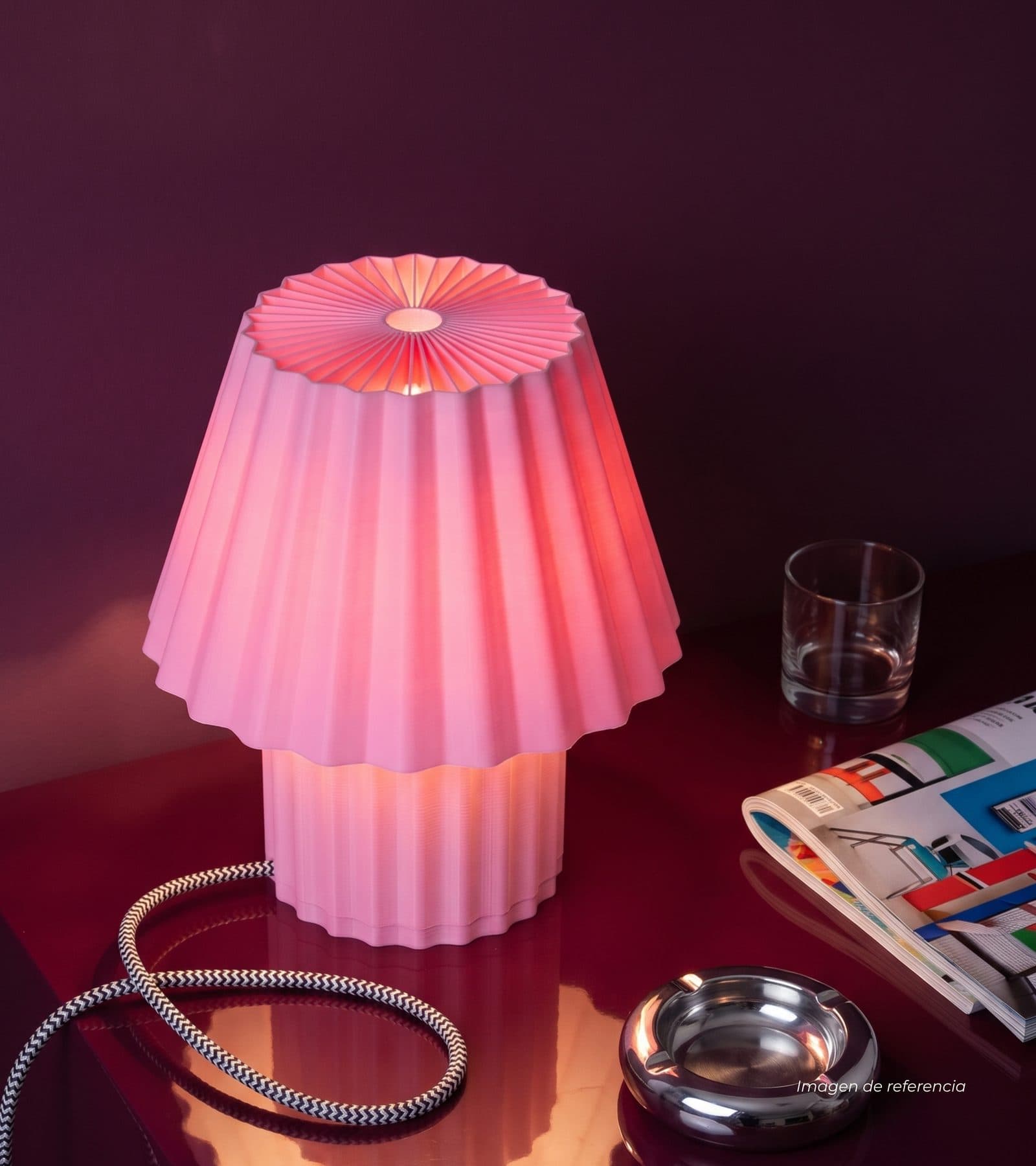 Lámpara Champi chicle encendida junto a un vaso y una revista