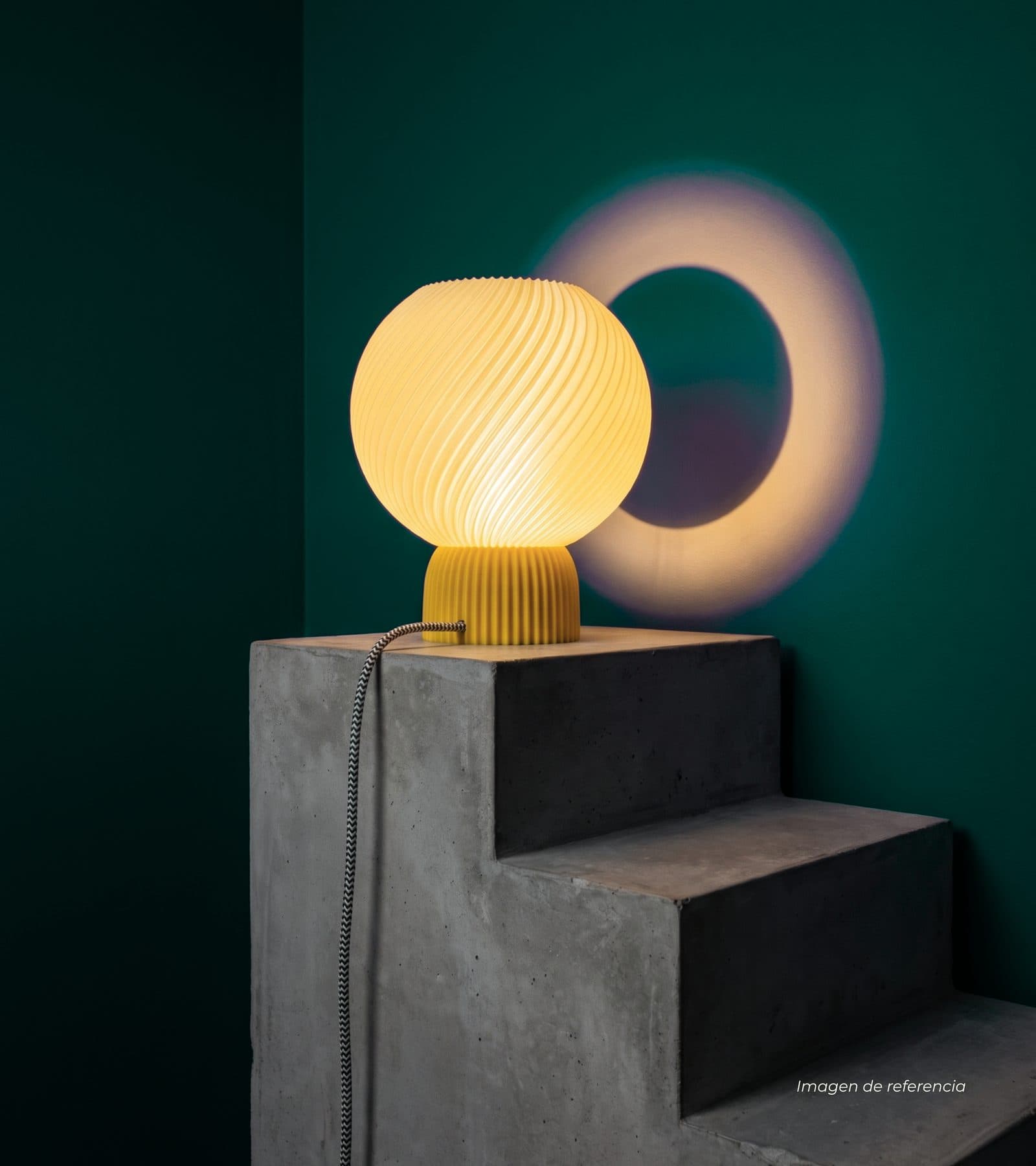 Lámpara Luna encendida sobre un bloque de concreto frente a una pared verde