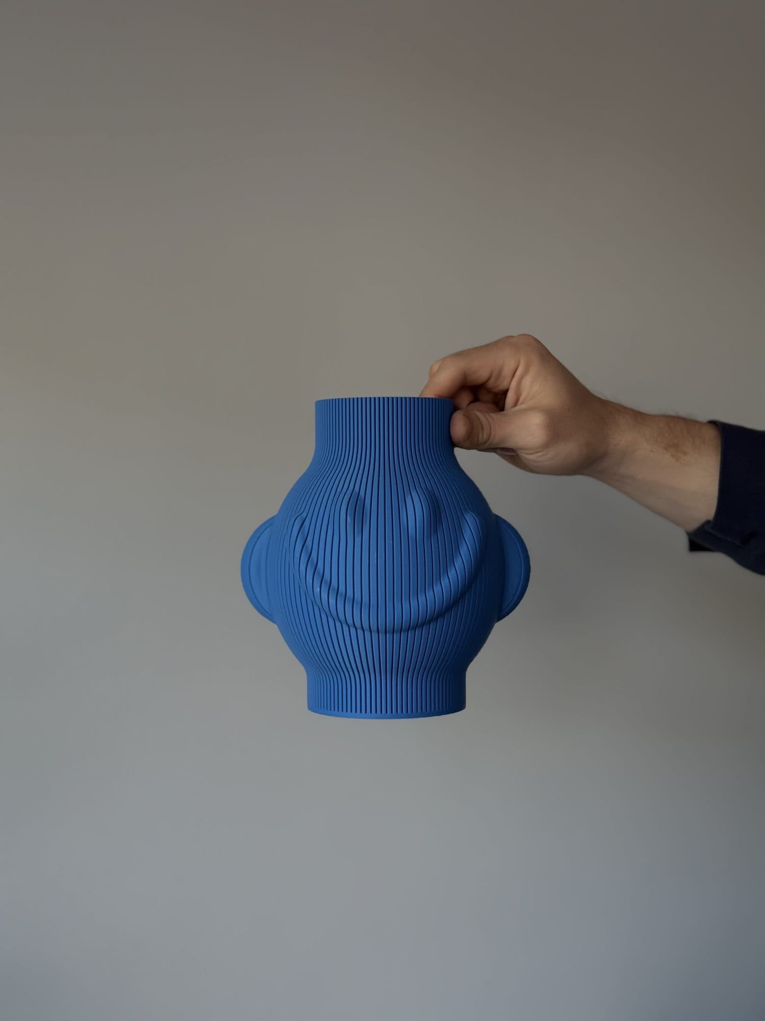 Jarrón Pepe azul con sonrisa, sostenido en una mano